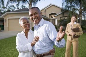 African American couple with real estate agent outside house